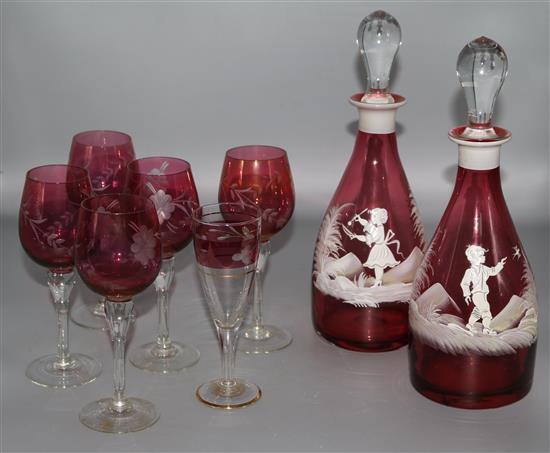 A pair of Mary Gregory ruby glass decanters, in a fitted case with other glasses